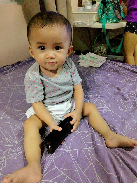 Photo portrait of cute baby girl sitting at home