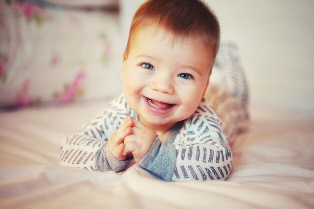 Photo portrait of cute baby laughing in bed at home