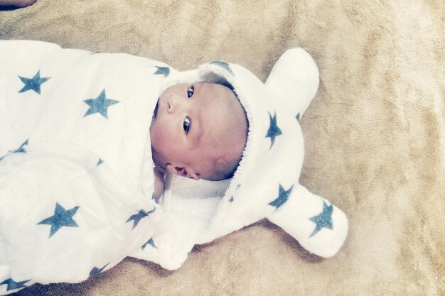 Photo portrait of cute baby lying on bed at home