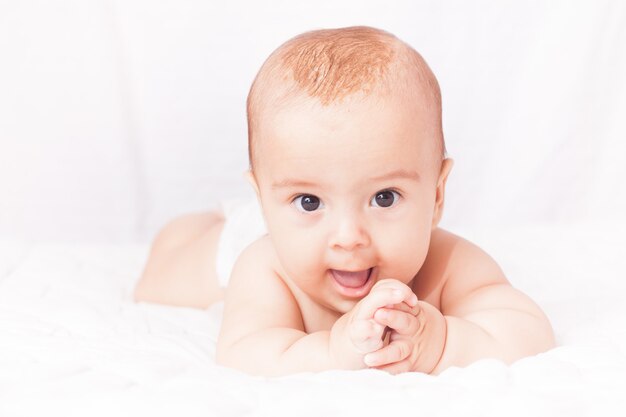 Portrait of a cute baby lying on the white textile