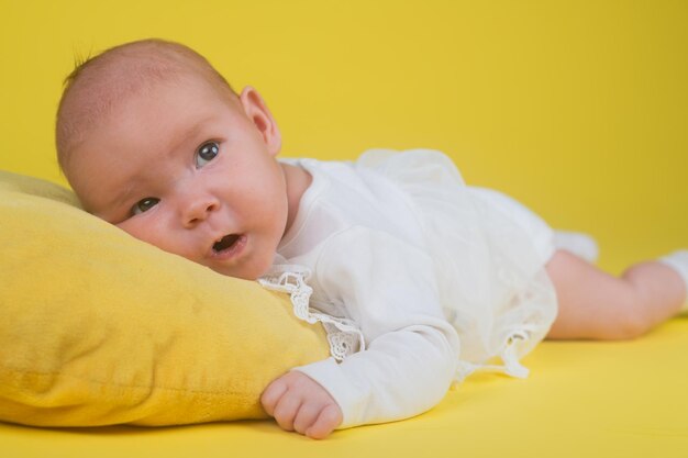 Portrait of a cute baby on a yellow background with copy space