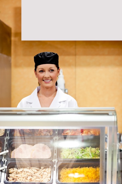 Portrait of a cute baker smiling at a customer in a  cafeteria