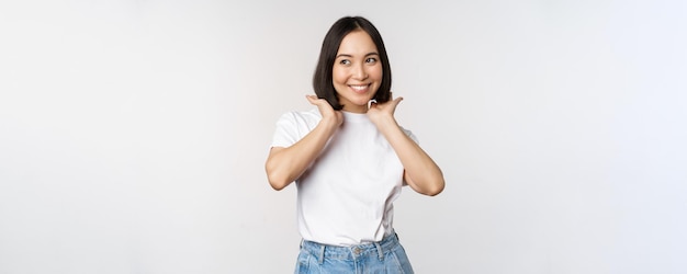 Portrait of cute beautiful asian woman touching her new short haircut showing hairstyle smiling happy at camera standing over white background