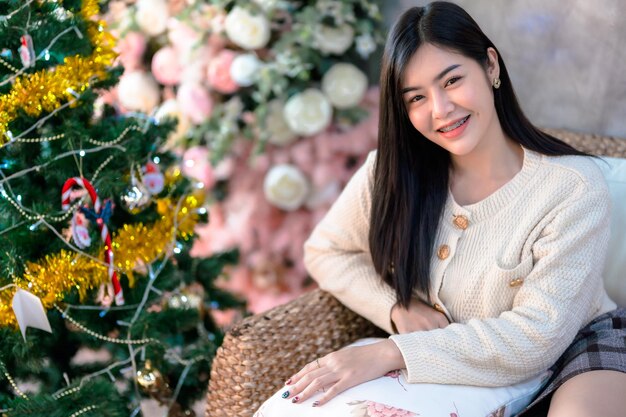 Portrait Cute beautiful positive smile young asian woman decorating to a Christmas tree at home in the living room indoors Decoration During Christmas xmas and New Year holidays