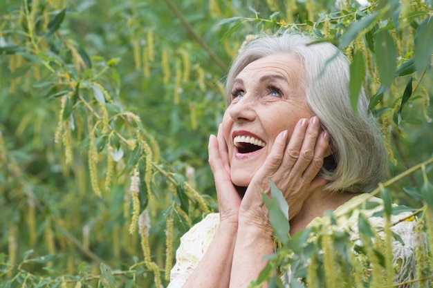 Портрет милой красивой пожилой женщины в зеленом парке
