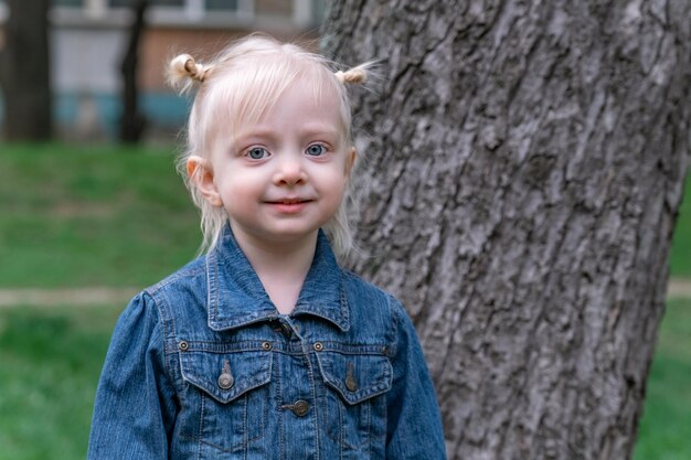 Portrait of cute blonde girl with two ponytails wearing denim jacket Caucasian child girl with big blue eyes