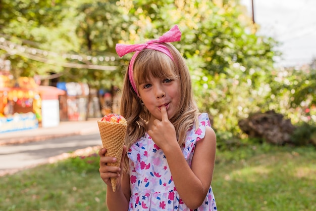 Portrait of a cute blonde little girl with ice cream on a walk in the park.
