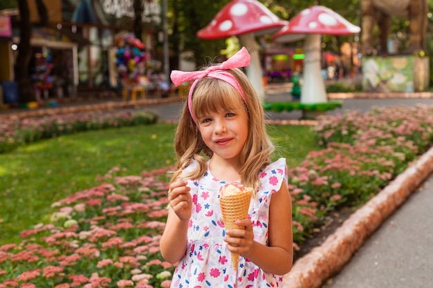 Portrait of a cute blonde little girl with ice cream on a walk in the park.
