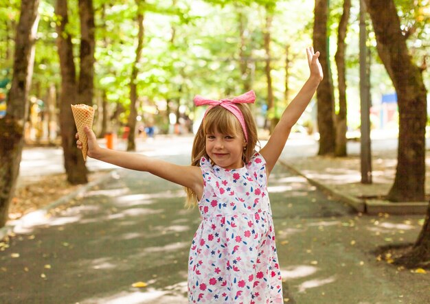 Portrait of a cute blonde little girl with ice cream on a walk in the park.
