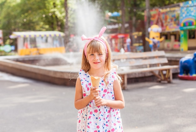 Ritratto di una bambina bionda carina con gelato durante una passeggiata nel parco.