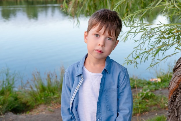 Portrait of a cute boy on the background of the lake in the park