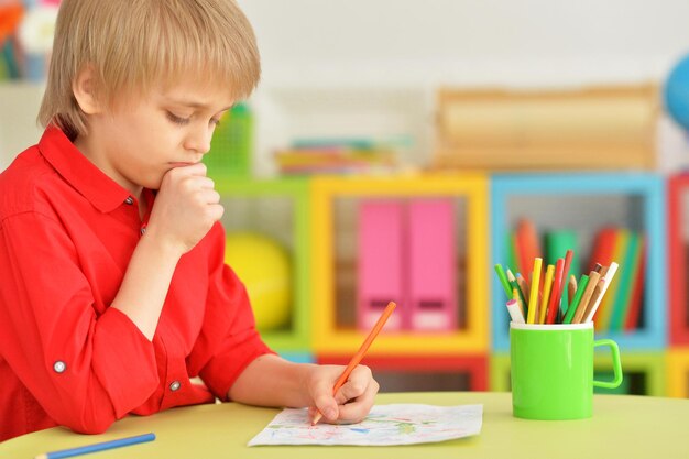 Портрет милого мальчика, рисующего карандашами