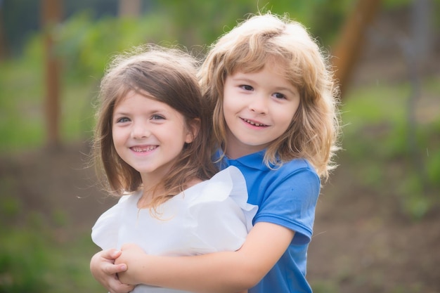 Portrait of cute boy and girl on summer field children in summer park cute kids face closeup playful