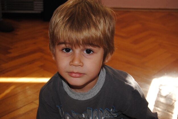 Photo portrait of cute boy on hardwood floor at home