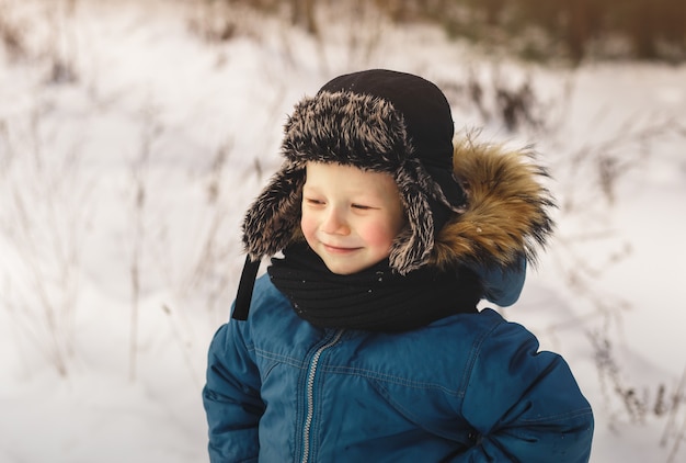 Портрет милого мальчика в шляпе зимой на открытом воздухе