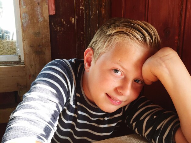 Photo portrait of cute boy leaning on hand at home