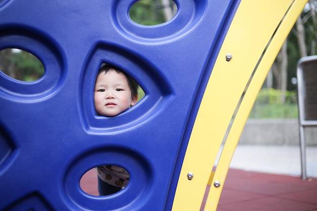 Photo portrait of cute boy looking through outdoor play equipment