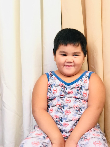 Portrait of cute boy sitting on bed at home