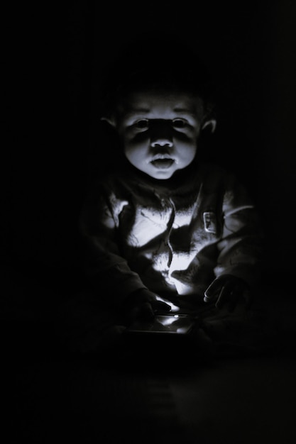 Photo portrait of cute boy sitting in dark