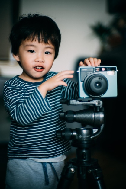 portrait of cute boy standing by camera at home