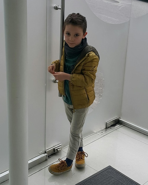 Foto ritratto di un ragazzo carino in piedi vicino al muro della stanza