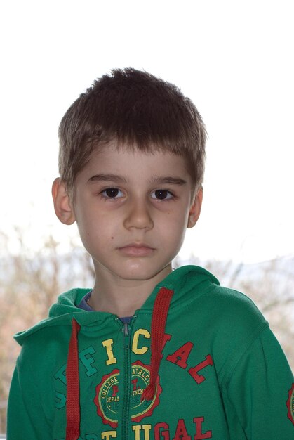 Portrait of cute boy wearing green hood outdoors