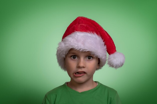 Photo portrait of cute boy wearing santa hat against green background