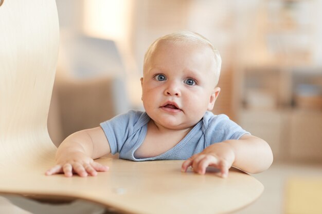 portrait of cute Caucasian toddler boy holding on chair