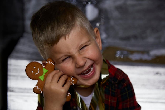 Portrait of cute cheerful toddler Cute boy plays with Christmas cookies among festive decorations Atmospheric home for New Year39s Eve Aesthetic cozy home Cheerful baby boy Joyful concept