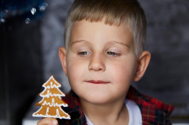 Foto ritratto di carino bambino allegro ragazzo carino con biscotti di natale tra decorazioni festive casa atmosferica per la vigilia di capodanno intimità domestica estetica bambino allegro concetto gioioso