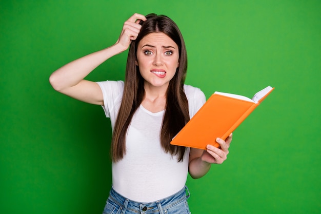 Portrait of cute confused young woman hold book not understand wear casual t-shirt isolated on green background