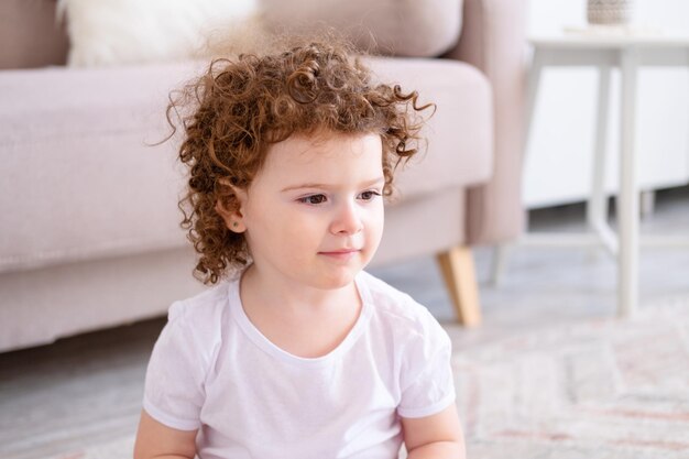 自宅で茶色の目を持つかわいい巻き毛の笑顔の子供の女の子の肖像画