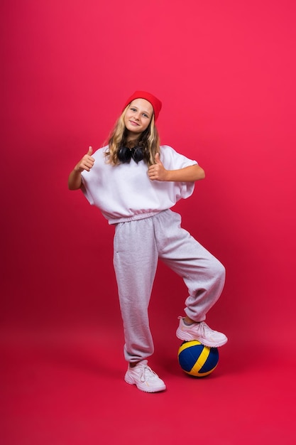 Portrait of a cute eight year old girl in volleyball outfit isolated on red yellow background