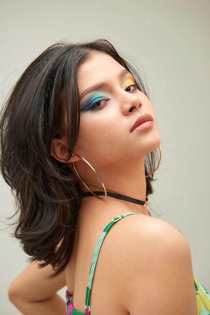 Portrait of cute female model in party makeup standing over gray background