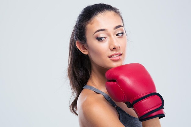 Ritratto di una donna carina fitness con guantoni da boxe in piedi isolato su un muro bianco