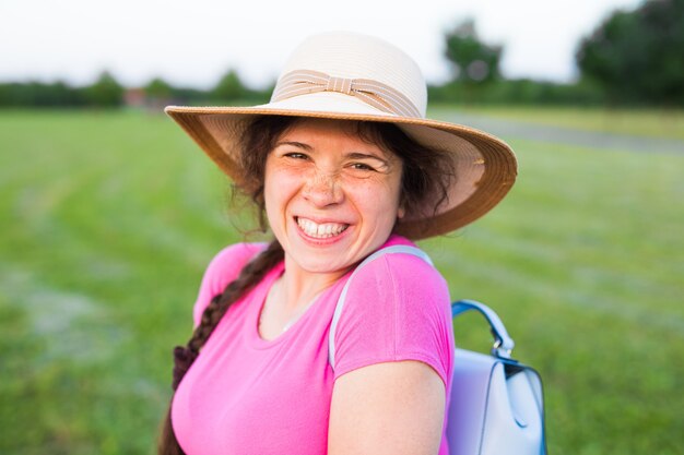 Portrait on cute funny laughing woman with freckles in hat in nature