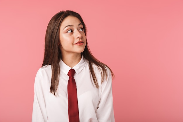 Portrait of cute girl 15-16y in school uniform standing, isolated over red wall