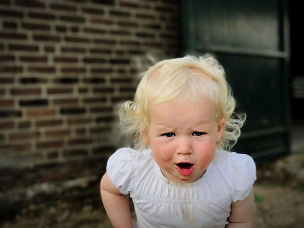 Portrait of cute girl against brick wall