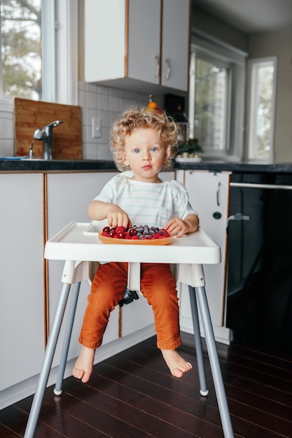 portrait of cute girl eating berries at home