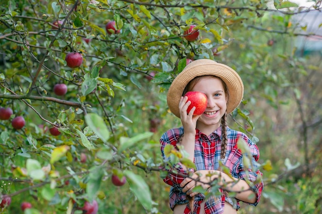 Portrait of a cute girl in a farm garden with a red apple Autumn harvest of apples