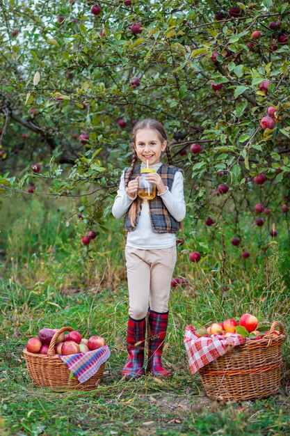 Portrait of a cute girl in a farm garden with a red apple Autumn harvest of apples