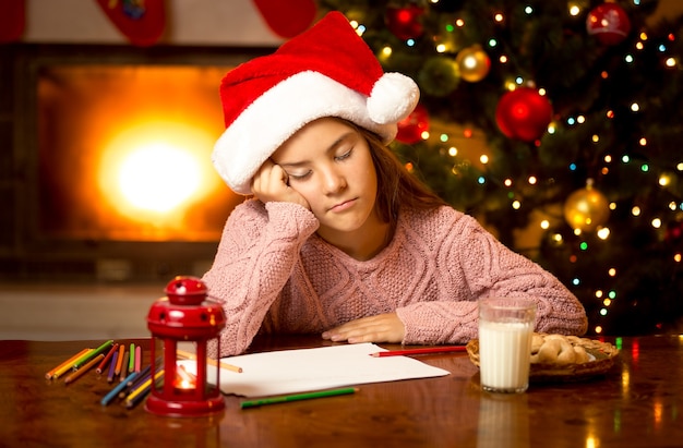 Portrait of cute girl fell asleep while writing letter to Santa