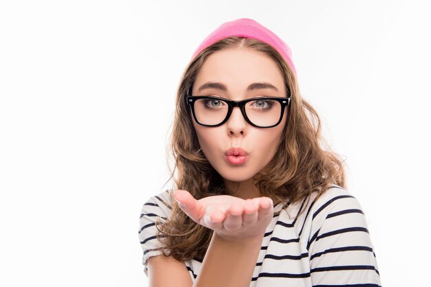 Portrait of cute  girl in hat and glasses sending air kiss