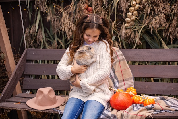 portrait of a cute girl holding a fluffy rabbit in the fall in the yard