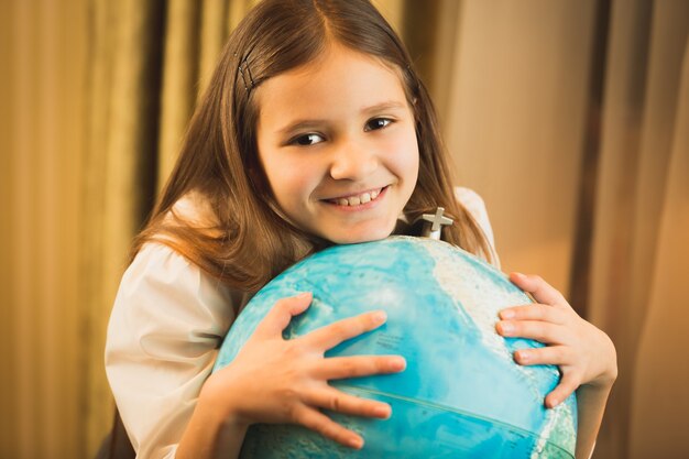 Portrait of cute girl holding hand on globe