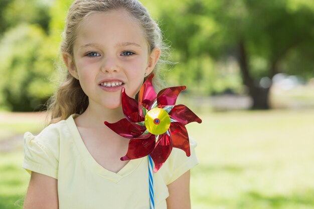 Foto ritratto della ragazza sveglia che tiene girandola al parco