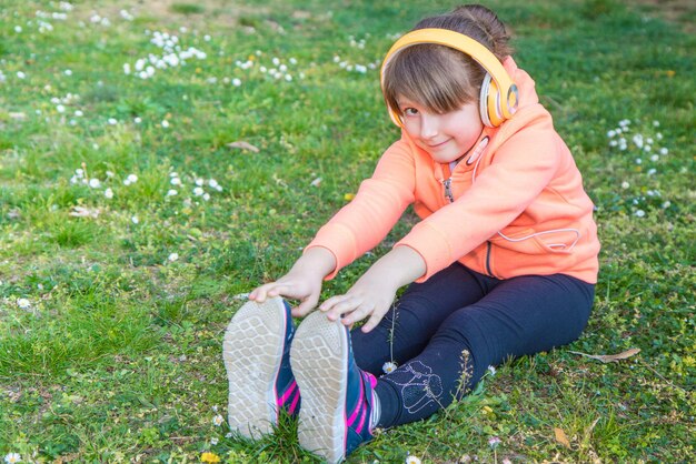 Foto ritratto di una ragazza carina che ascolta musica mentre si esercita sulla terra nel parco