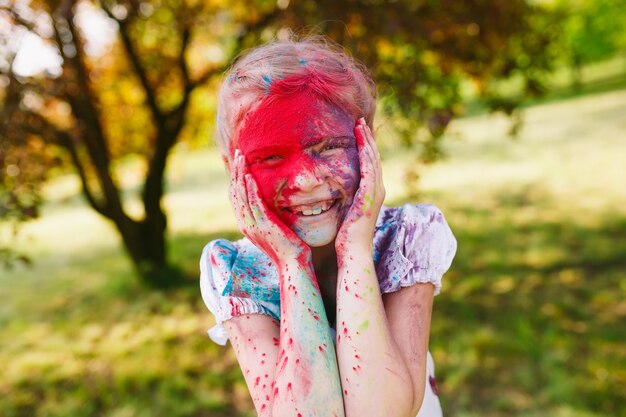 Portrait of a cute girl painted in the colors of Holi festival.