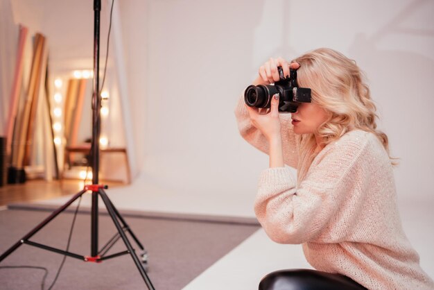 Foto ritratto di una ragazza carina fotografa che scatta foto in uno studio fotografico