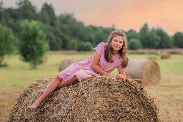 Portrait of cute girl resting in a field on hay Summer holidays in the countryside